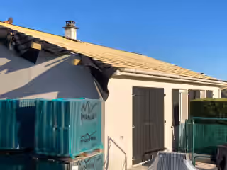 Maison en rénovation de toiture, voliges posées et palettes de tuiles neuves au pied du mur