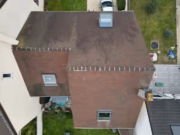 Vue d’en haut d’une toiture en tuiles couverte de mousse, avant nettoyage